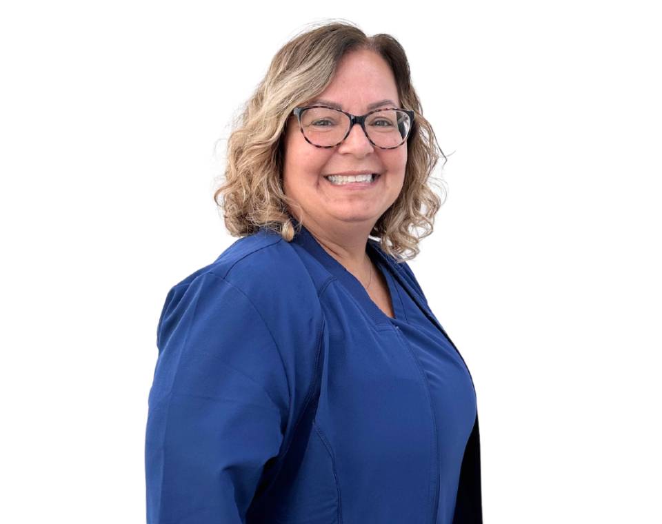 Smiling person with glasses and curly hair wearing a blue jacket.