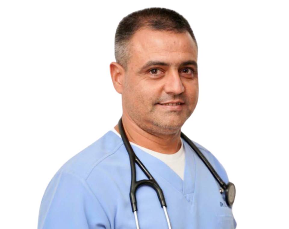 A man in a light blue scrubs with a stethoscope around his neck smiles slightly.