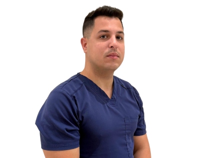 Person wearing navy blue scrubs, standing against a white background.