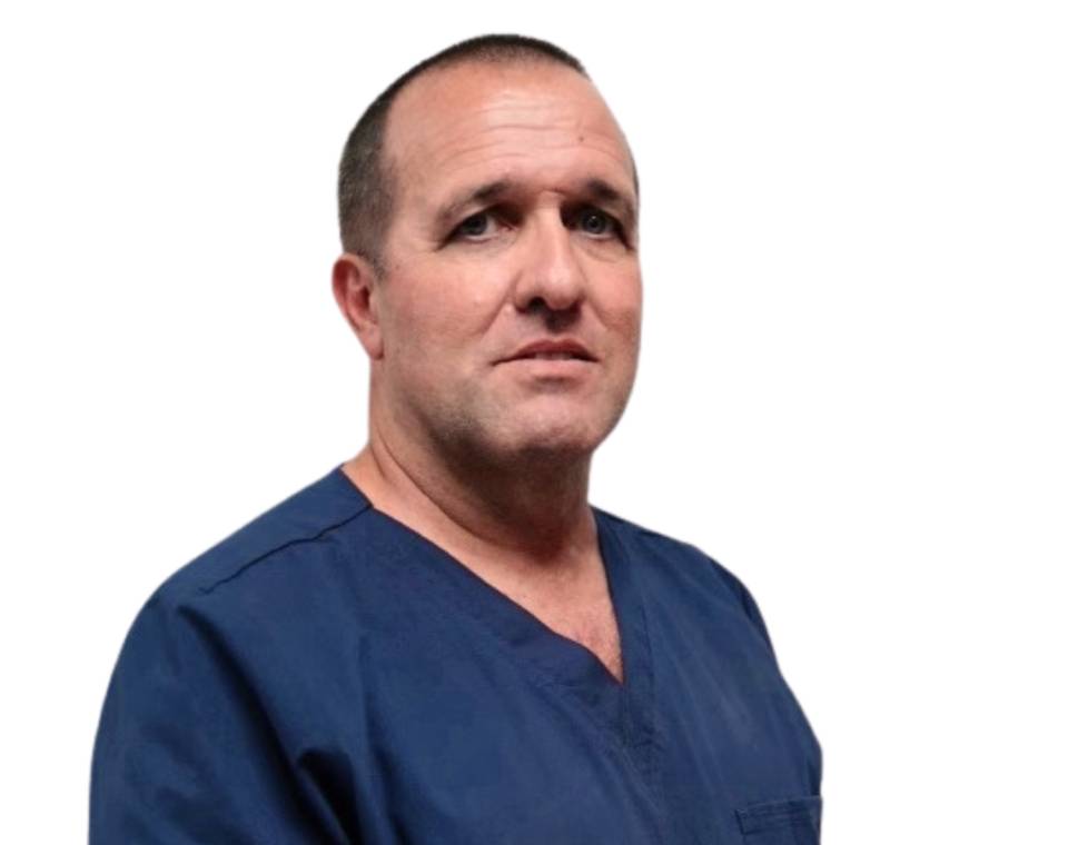 Man in blue scrubs looking directly at the camera.