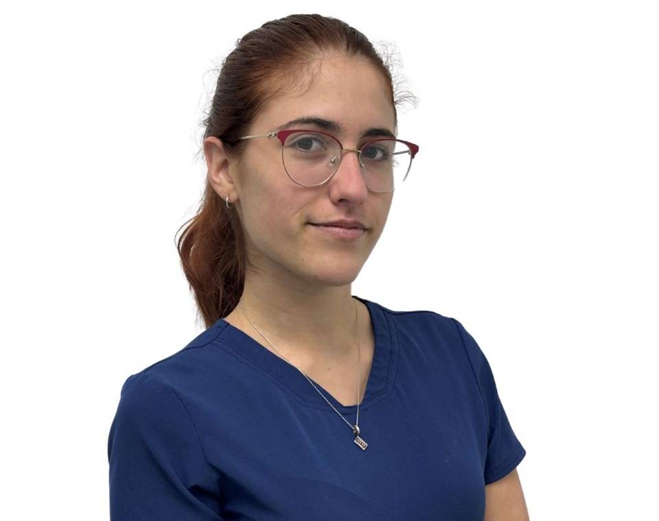 Woman with glasses and brown hair in a ponytail wearing a blue top, looking at the camera.